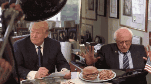 donald trump and bernie sanders sit at a table with a plate of food on it