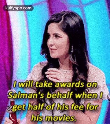 a woman is holding a trophy and talking into a microphone while holding a trophy .