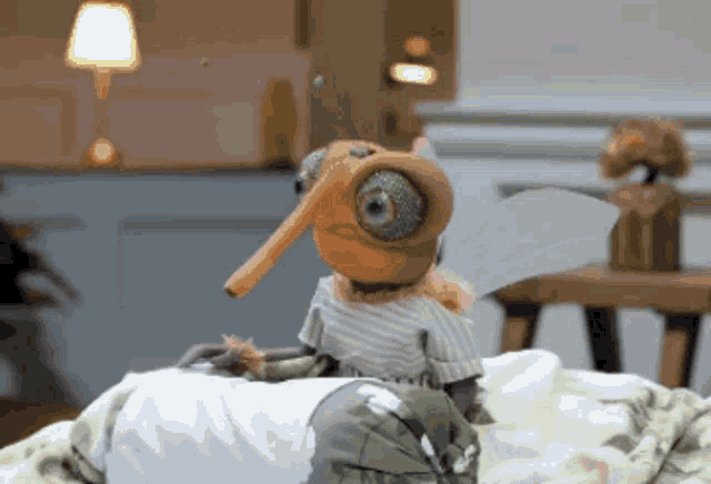 a stuffed animal with a long nose and wings is sitting on a bed