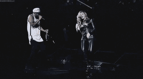 a man wearing a jersey with the number 4 on it stands next to a woman singing into a microphone ..