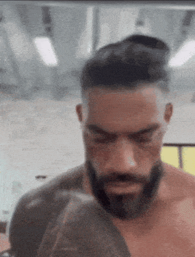 a man with a beard and a tattoo on his arm is standing in a gym .