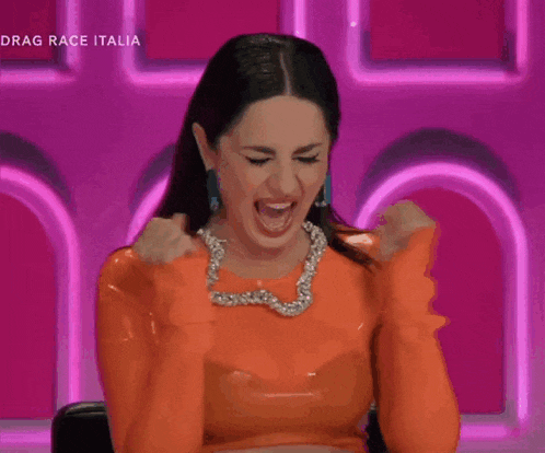 a woman in an orange dress is screaming with the words drag race italia on the bottom right