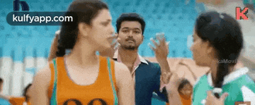 a man and two women are standing next to each other in a stadium and talking to each other .