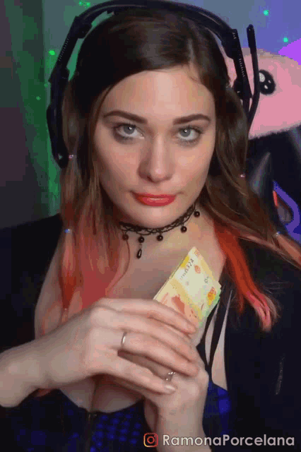 a woman wearing headphones and a choker is holding a card that says ' ramona porcelana ' on it
