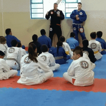 a group of people are sitting on a mat with a man standing behind them