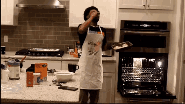 a man wearing an apron that says ' nuts ' on it holds a pan of food