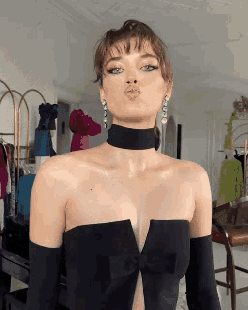 a woman wearing a choker and earrings is blowing a kiss at the camera