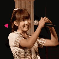 a girl is singing into a microphone with a pink heart in her hair