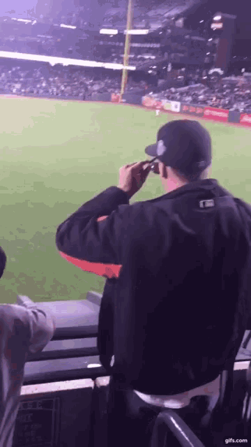 a man taking a picture of a baseball field with a cell phone