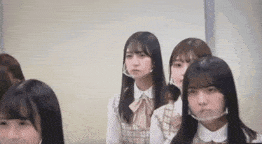 a group of young girls wearing face masks are sitting in a classroom .