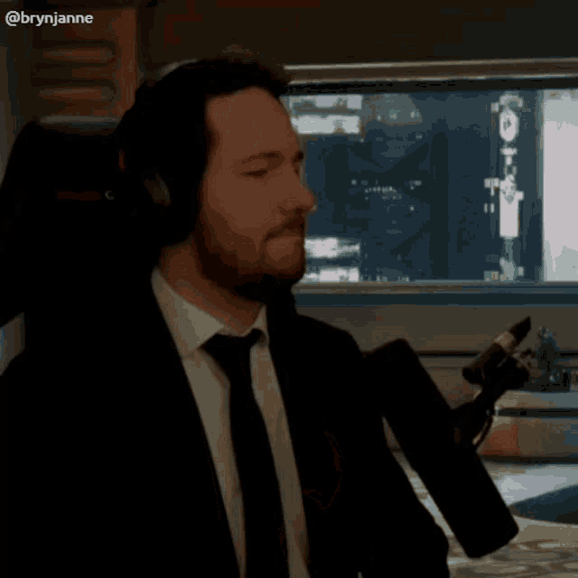 a man wearing headphones and a tie gives a thumbs up sign