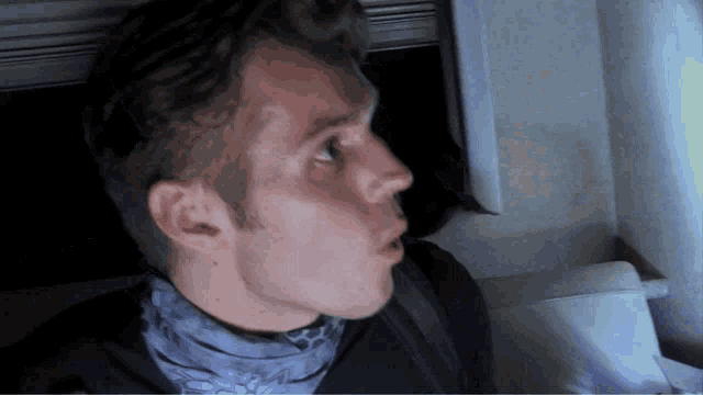 a man wearing a scarf around his neck looks up at something