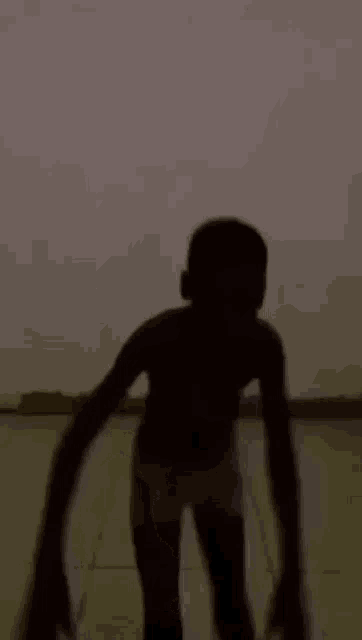 a silhouette of a young boy standing on a tiled floor in front of a wall .