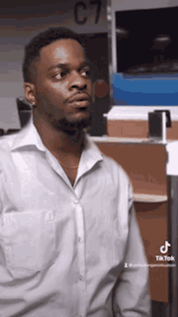 a man in a white shirt is standing in front of a counter with the number c7 on it
