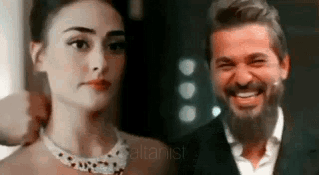 a man and a woman are smiling and looking at each other . the woman is wearing a necklace .