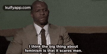 a man in a suit and tie is sitting in a chair and talking about feminism .