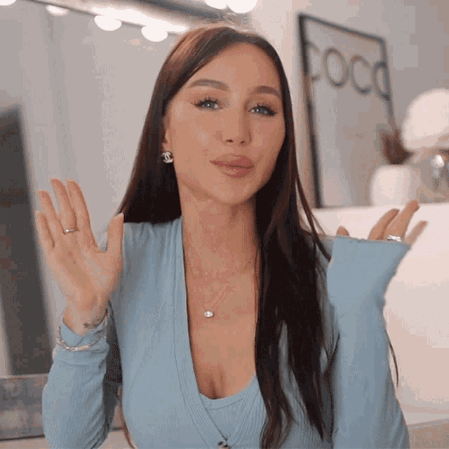 a woman in a blue top stands in front of a mirror with the word coco on it