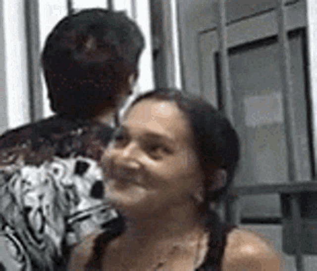 a woman is smiling while standing next to a man in a black and white shirt .