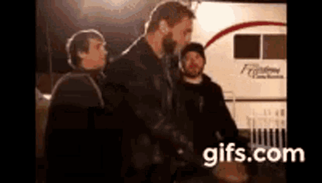 a group of men standing next to each other in front of a rv .