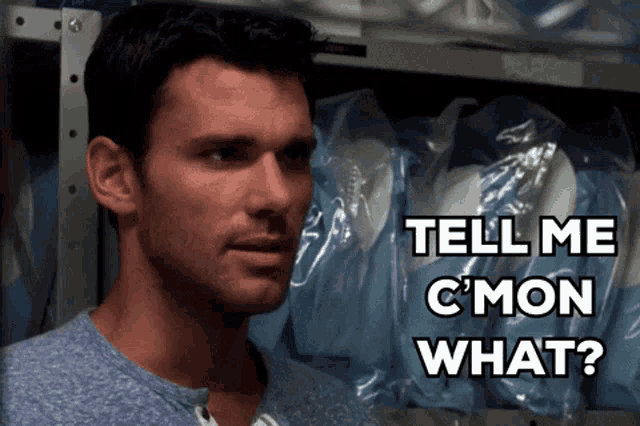a man stands in front of a shelf with plastic bags and says tell me c mon what