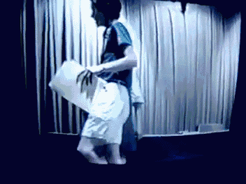 a man in a blue shirt is holding a white pillow
