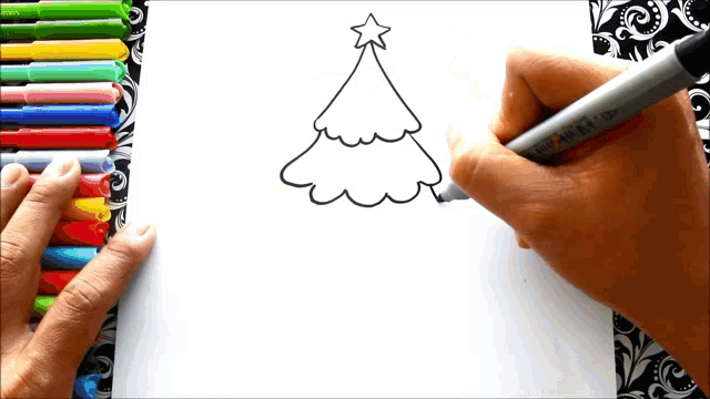 a person is drawing a christmas tree with markers