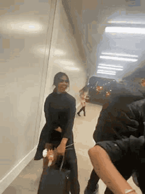 a woman is holding a suitcase while walking down a hallway with a man .