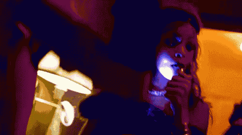 a woman smoking a cigarette in a dark room with a sign that says exit