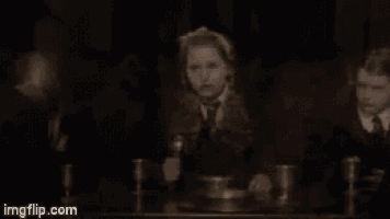 a woman is sitting at a table with a fork and spoon in her hand .