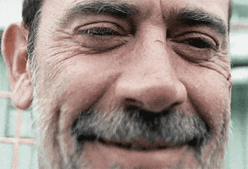 a man with a beard is smiling and looking at the camera