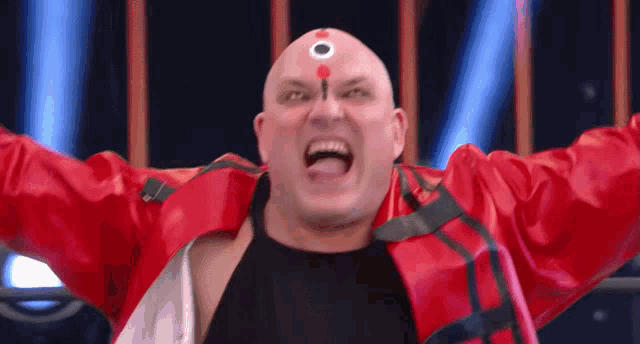 a bald man in a red jacket has a circle on his forehead