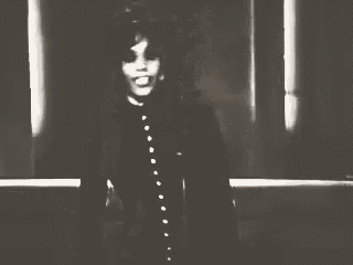 a black and white photo of a woman in a black coat dancing .