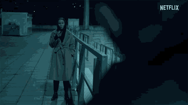 a woman in a trench coat stands on a balcony with a netflix logo in the background