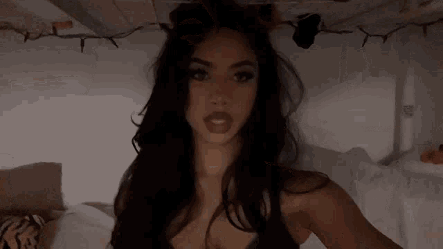 a woman with long dark hair is taking a selfie in a bunk bed .