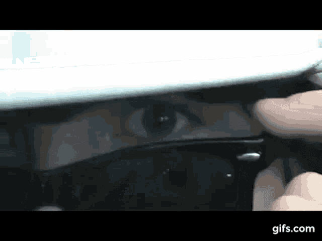 a close up of a person 's eye looking through sunglasses .