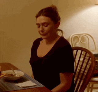 a woman is sitting at a table with a bowl of food on the table .