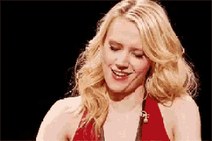 a woman in a red dress is smiling and looking down at something .