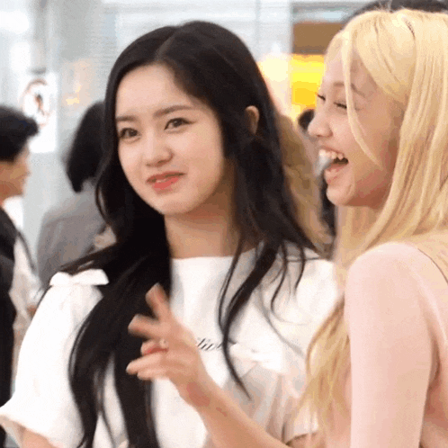 two girls are standing next to each other and laughing . one of the girls is wearing a white shirt .