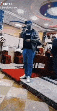a man is singing into a microphone while standing on a stage in a room .