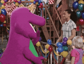 a purple stuffed animal is standing next to a girl with balloons