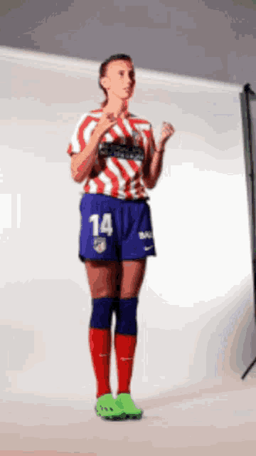 a woman wearing a red and white striped shirt with the number 14 on the shorts