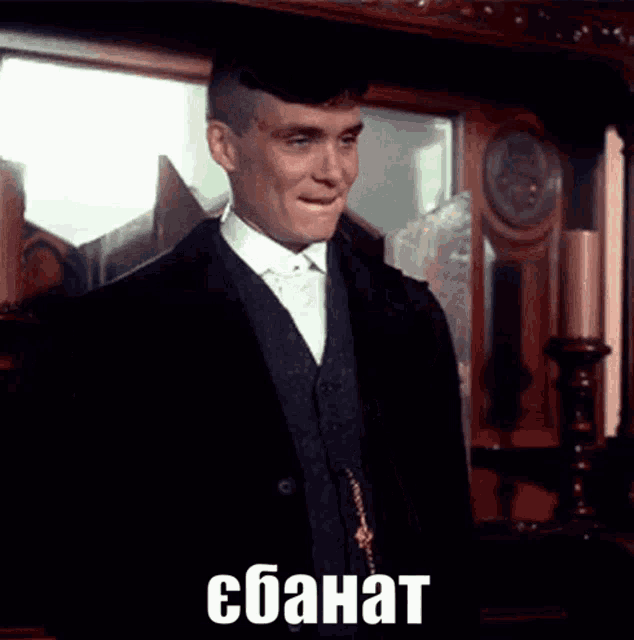 a man in a suit and tie is standing in front of a mirror with the word ebanat written on the bottom