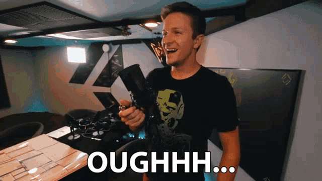 a man in a black shirt holds a remote control and says " ouhhhh "