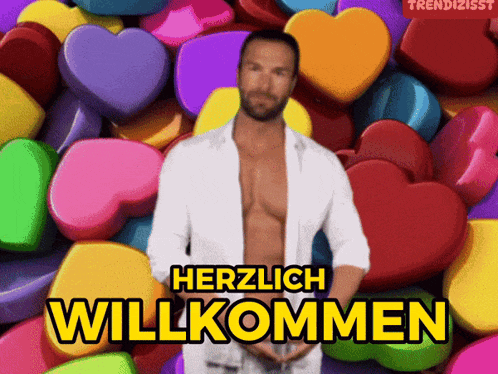 a man in a white shirt is standing in front of a bunch of colorful hearts and the words herzlich willkommen