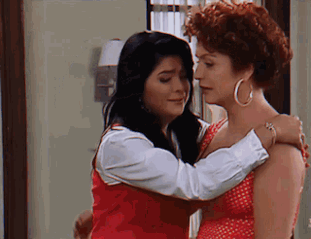 two women are hugging each other and one has hoop earrings