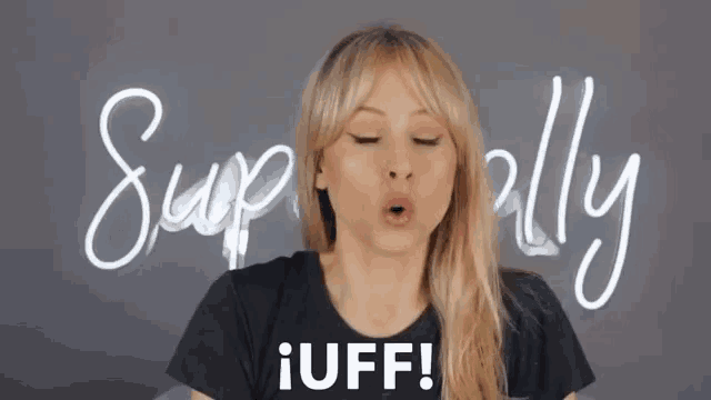 a woman in a black shirt says iuff in front of a neon sign that says superally
