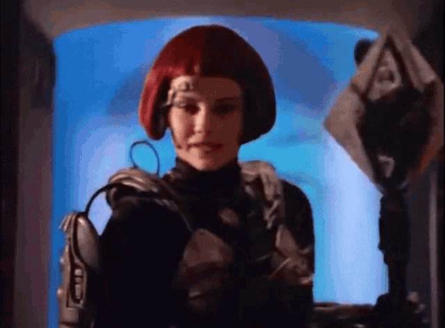 a woman in a red wig is standing in a room with a blue background .
