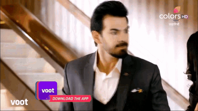 a man in a suit is walking down a set of stairs with a purple sign that says voot