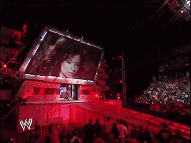 a woman is walking on a stage with the name candice michelle on the screen behind her