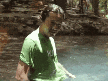 a man in a green shirt that says hulk is standing in a body of water